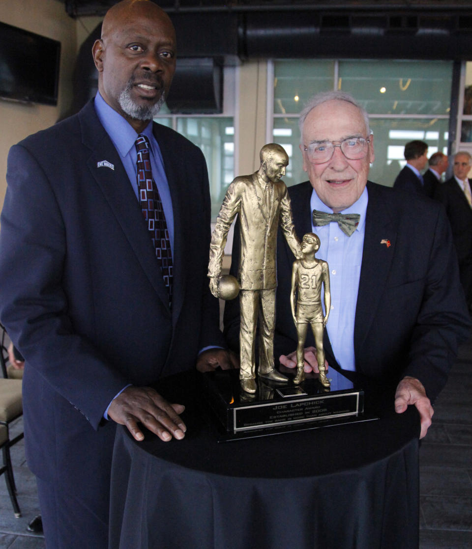 FILE - Fred Carter, left, poses for a photo with his former Mount St. Mary's NCAA college basketball head coach Jim Phelan, and the Lapchick Character Award statue at a presentation luncheon in New York, in this Thursday, Nov. 17, 2011, file photo. Carter introduced Phelan for the award recognizing basketball coaches of "both exemplary character and coaching ability." Phelan, the bow-tied basketball coach who won 830 games during nearly a half-century at Mount St. Mary's, has died. He was 92. The athletic department at Mount St. Mary's said Phelan died in his sleep at home Tuesday night. (AP Photo/Bebeto Matthews)