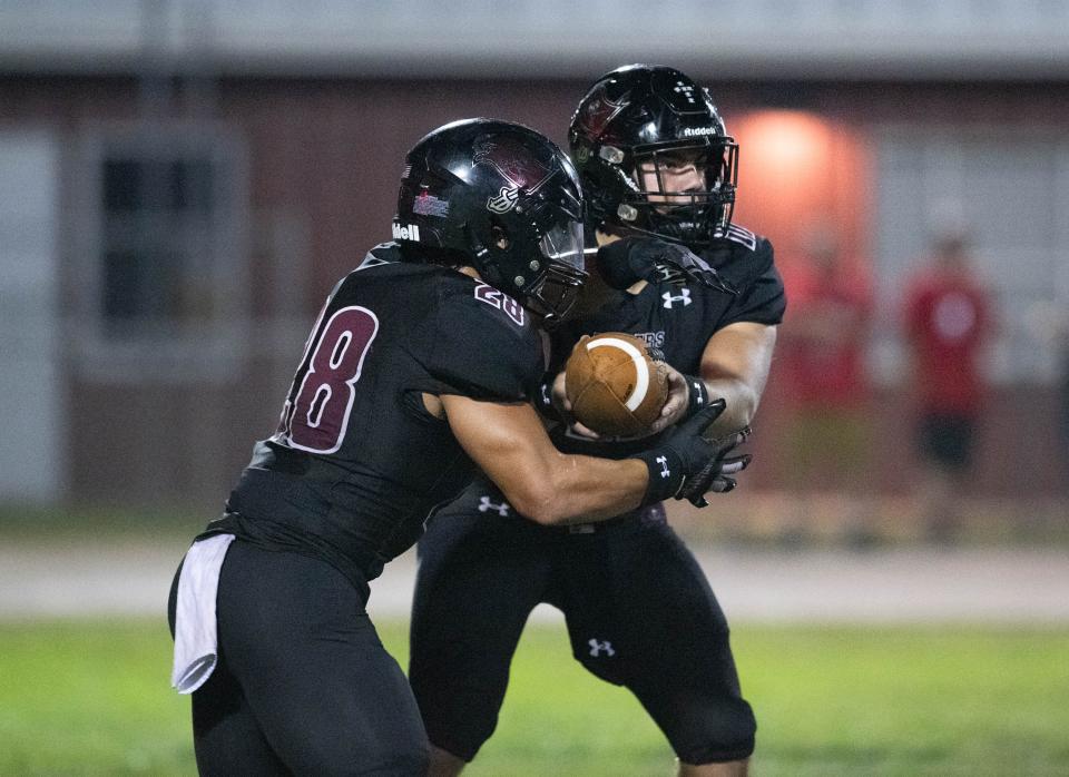 Quarterback Hunter Pfiester (11) hands off to Connor Mathews (28) during the Tate vs Navarre football game at Navarre High School on Friday, Sept. 15, 2023.