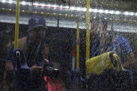 Journalists look at a broken window on an official media bus after it shattered when driving accredited journalists to the Main Transport Mall from the Deodoro venue of the Rio 2016 Olympic Games. REUTERS/Shannon Stapleton