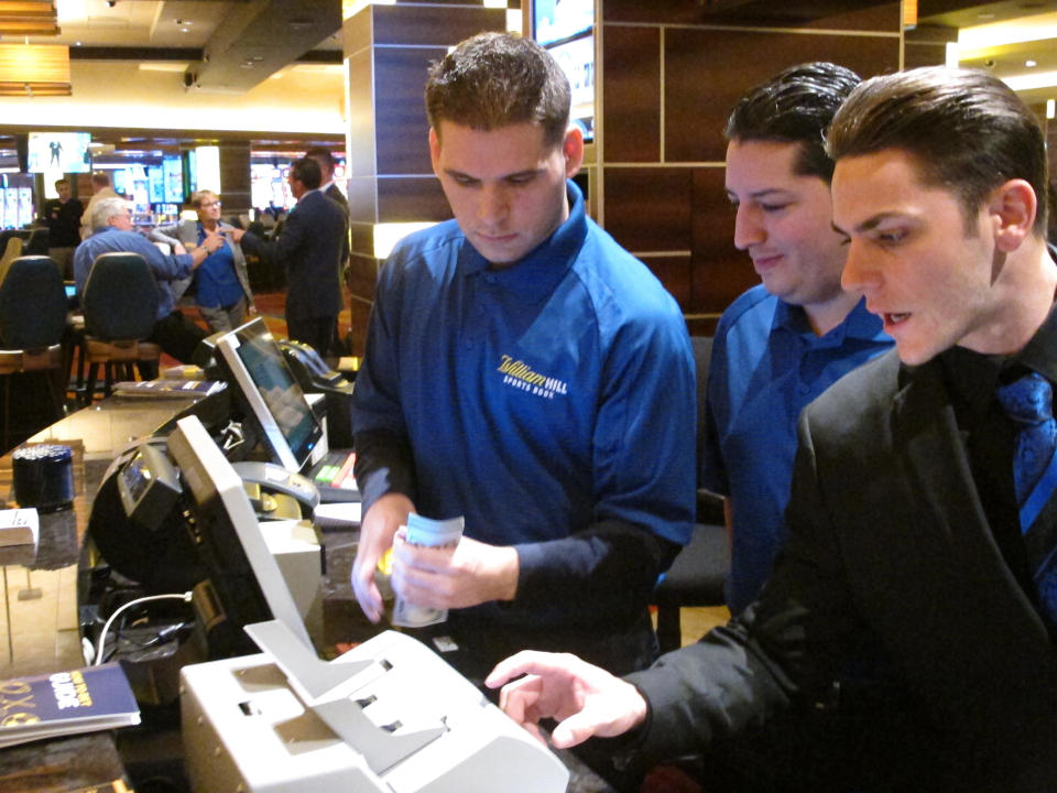 This Oct. 25, 2018 photo, employees at the sports book at the Tropicana casino in Atlantic City N.J. count money moments before it opened. Gambling companies in the U.S. are increasingly bringing different forms of gambling together, including sports betting, casino gambling, internet gambling and daily fantasy sports, and partnering with media companies as they seek to increase revenue. (AP Photo/Wayne Parry)