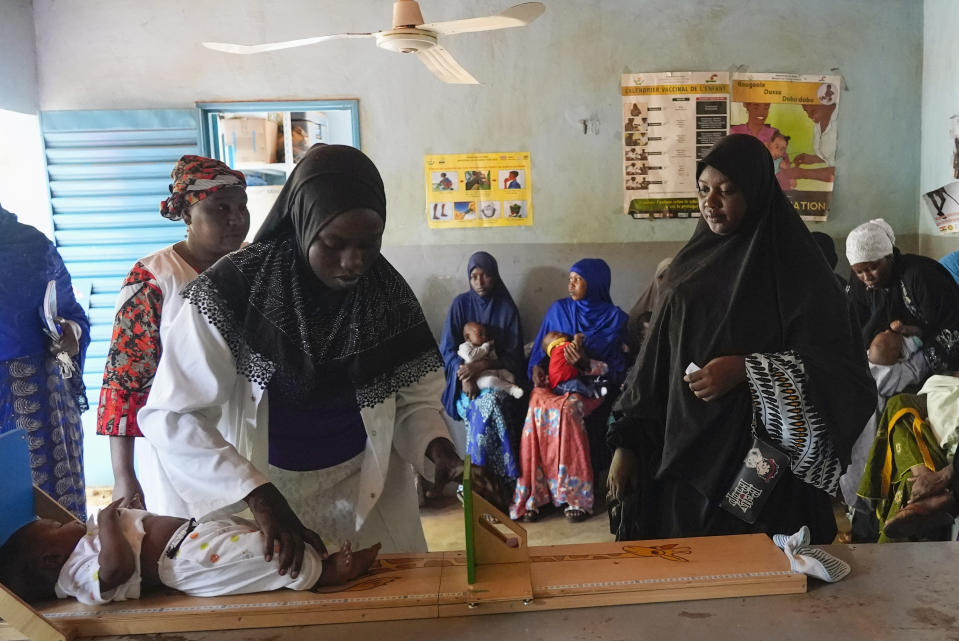 Women gather at a clinic to have their children vaccinated in Niamey, Niger, Monday, Aug. 21, 2023. Severe economic and travel sanctions imposed by the West African regional bloc ECOWAS after mutinous soldiers ousted the country's democratically elected president in July, are taking a toll on Nigeriens and causing concern for health workers. (AP Photo/Sam Mednick)