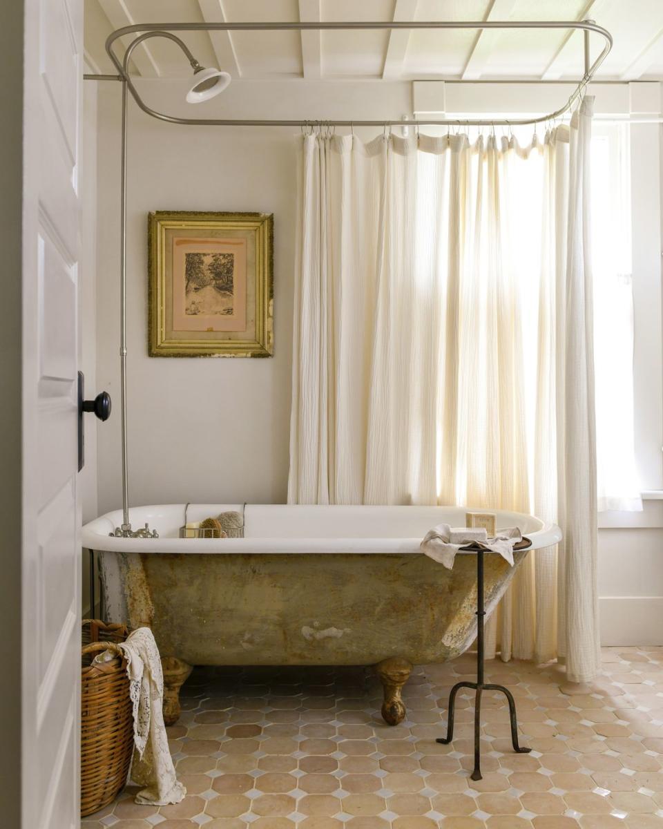 clawfoot tub in rustic bathroom with terra cotta floors