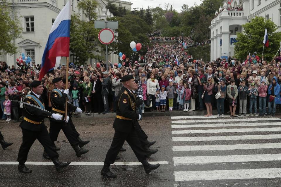 Russian marines carry national flag as local residents gather along the street during a Victory Day military parade, which commemorates the 1945 defeat of Nazi Germany, in Sevastopol, Russia, on Friday, May 9, 2014. Russia marks the Victory Day on May 9 and Sevastopol marks 70th anniversary of liberation from German troops. (AP Photo/Ivan Sekretarev)