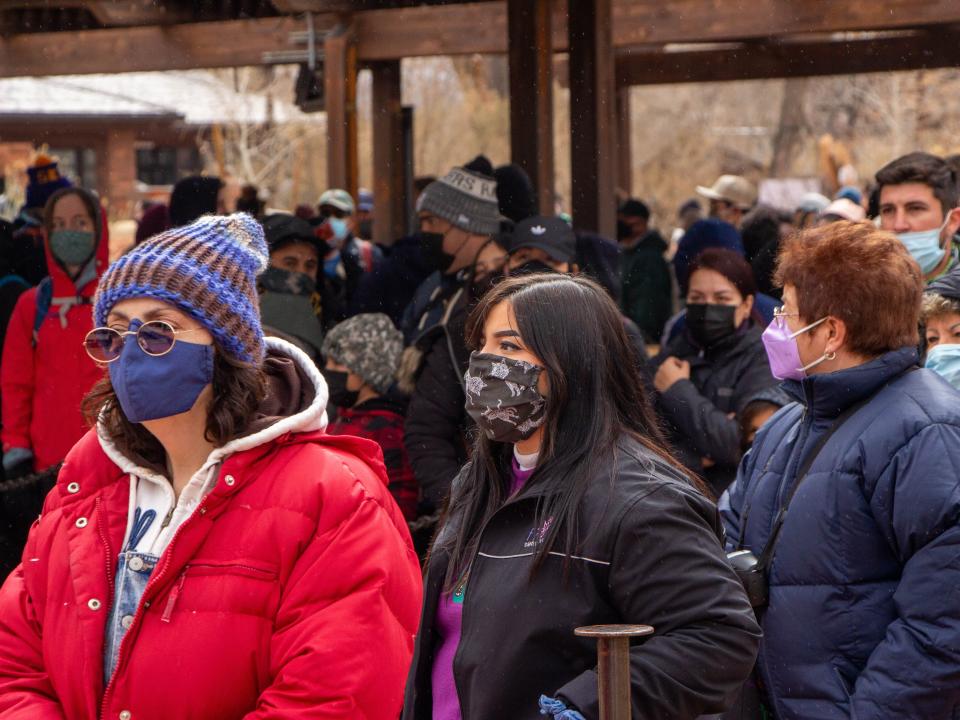 People in masks, jackets, and hats line up at Zion National Park.