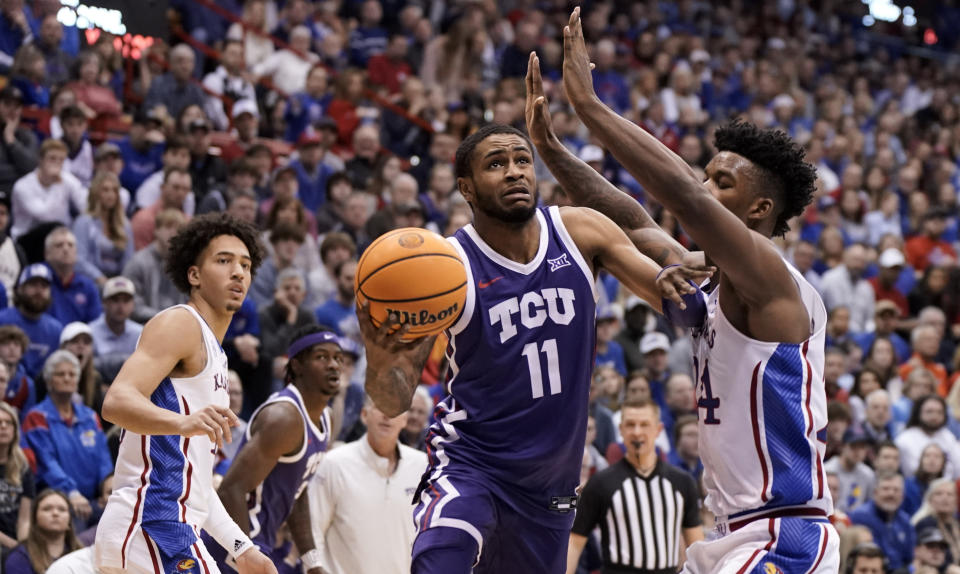 TCU guard Rondel Walker (11) gets past Kansas forward K.J. Adams Jr. (24) for a basket during the second half of an NCAA college basketball game on Saturday, Jan. 21, 2023, at Allen Fieldhouse in Lawrence, Kan. At left is Kansas forward Jalen Wilson (10). TCU defeated Kansas, 83-60. (AP Photo/Nick Krug)