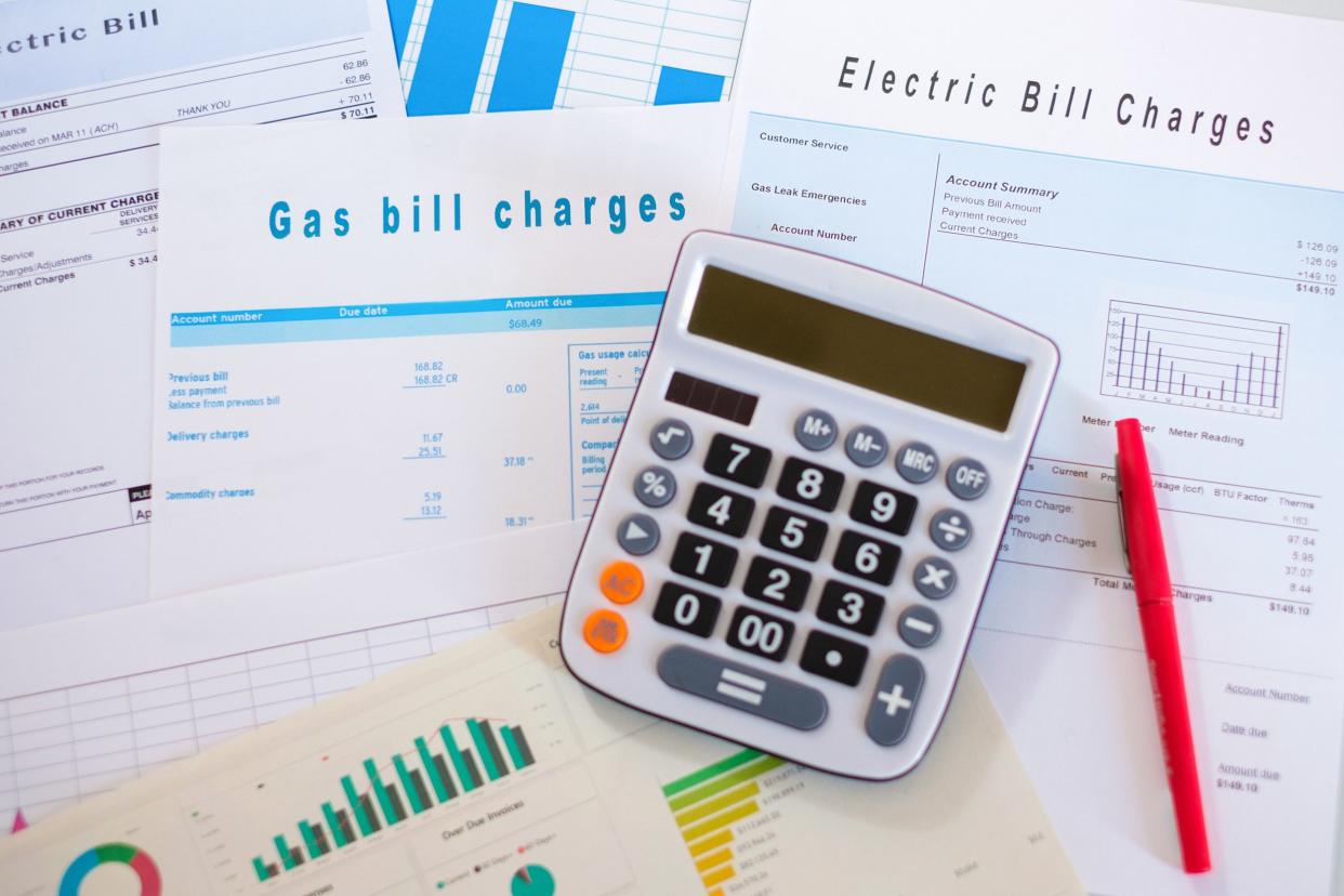 calculator and red pen on background of several utility bills and charts