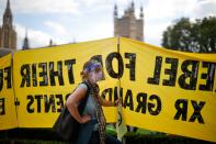 An activist from the climate protest group Extinction Rebellion wears a PPE face shield as she holds a placard in Parliament Square in London on September 1, 2020, at the start of their new season of "mass rebellions". - Climate protest group Extinction Rebellion will target Britain's parliament as part of "mass rebellions" starting from September 1. Other actions will take place around the country. (Photo by Tolga Akmen / AFP) (Photo by TOLGA AKMEN/AFP via Getty Images)