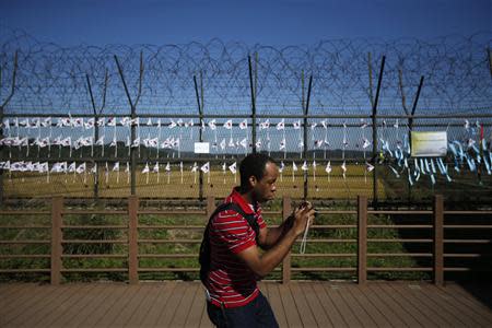 A visitor takes photographs in front of military fences decorated with South Korean national flags at the Imjingak pavilion near the demilitarized zone which separates the two Koreas, in Paju, north of Seoul October 16, 2013. REUTERS/Kim Hong-Ji