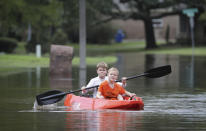 Josey Chambers, 11, and his brother Sawyer, 7, make they way on a kayak up Wandering Trail after Clear Creek overflowed as Tropical Storm Beta rained over the area Tuesday, Sept. 22, 2020, in Friendswood, Texas. (Steve Gonzales/Houston Chronicle via AP)