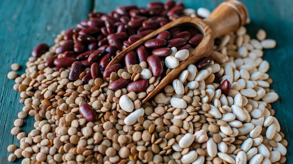 Legumes in a container tipped over onto wooden table