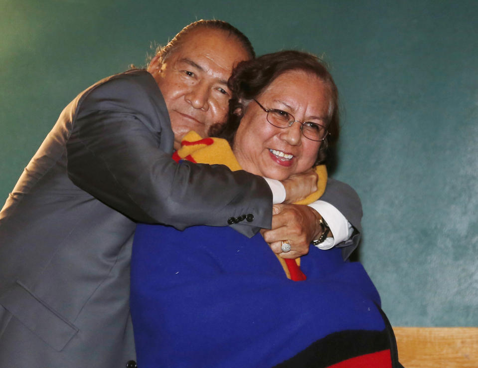 Amaryllis Frazier, right, of Indiahoma, Okla., receives a hug from Comanche Nation Chairman Wallace Coffey, left, after he presented her with a blanket during a ceremony to honor the Comanche Code Talkers in Lawton, Okla, Thursday, Sept. 26, 2013. Frazier's father, Forrest Kassanavoid, was a code talker. (AP Photo/Sue Ogrocki)