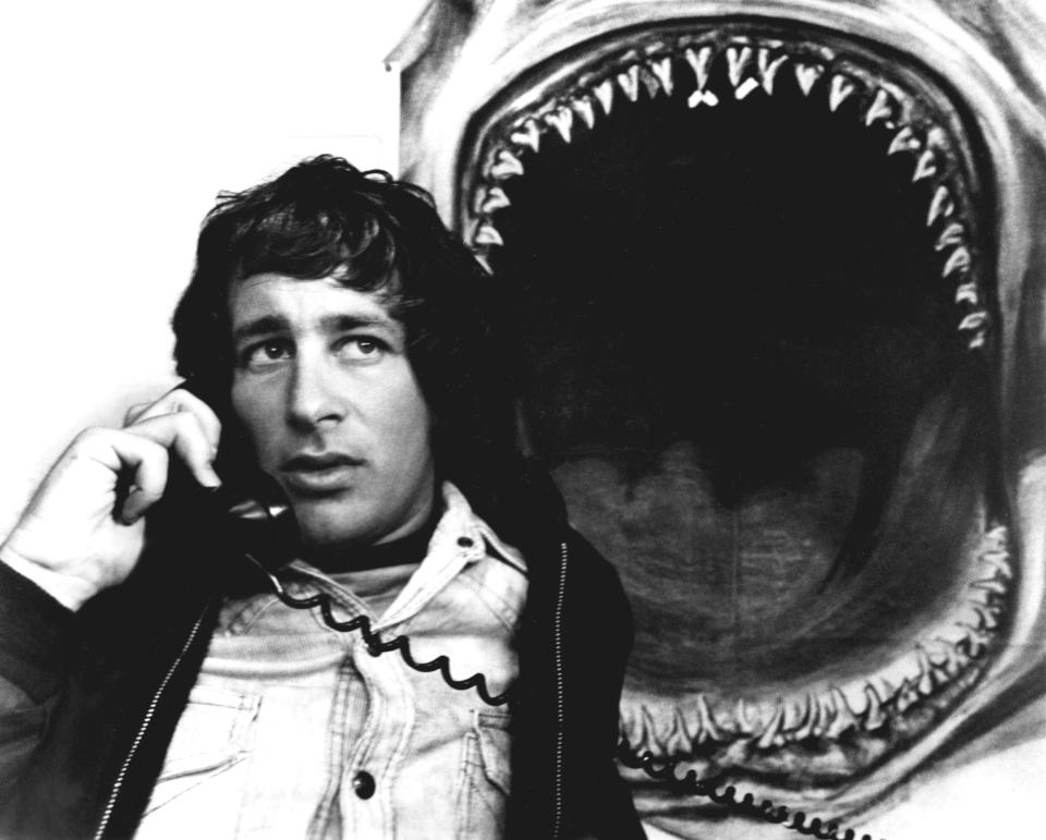 A young Stephen on a landline phone with an illustration of a shark with it's mouth wide open behind him