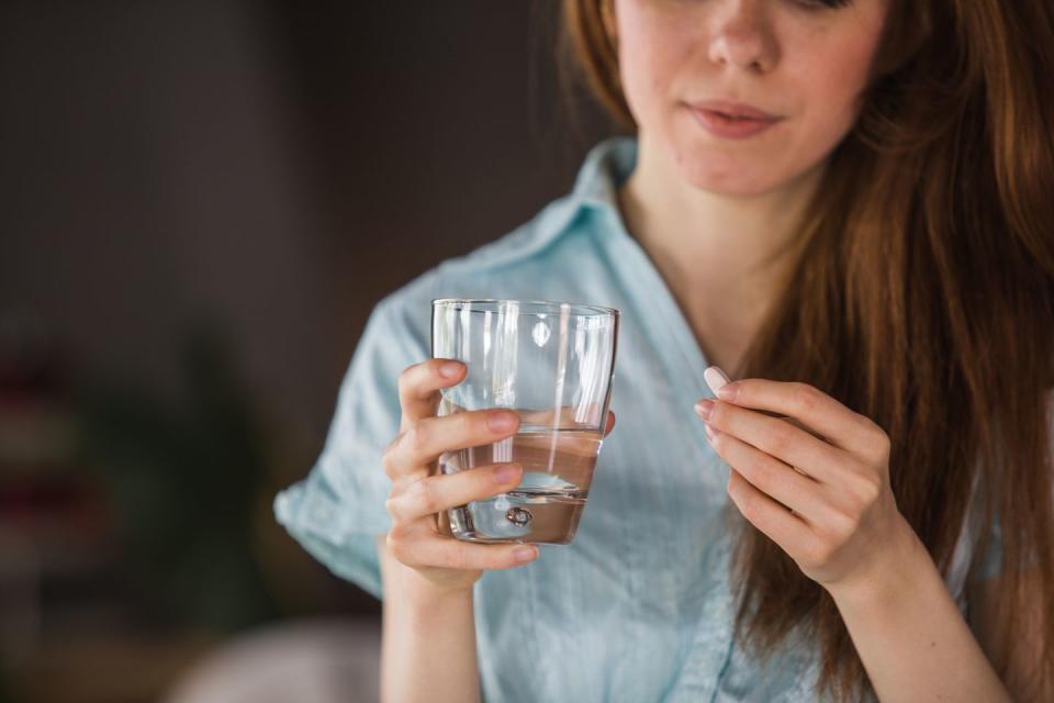 woman holding a glass of water and medication in her hand