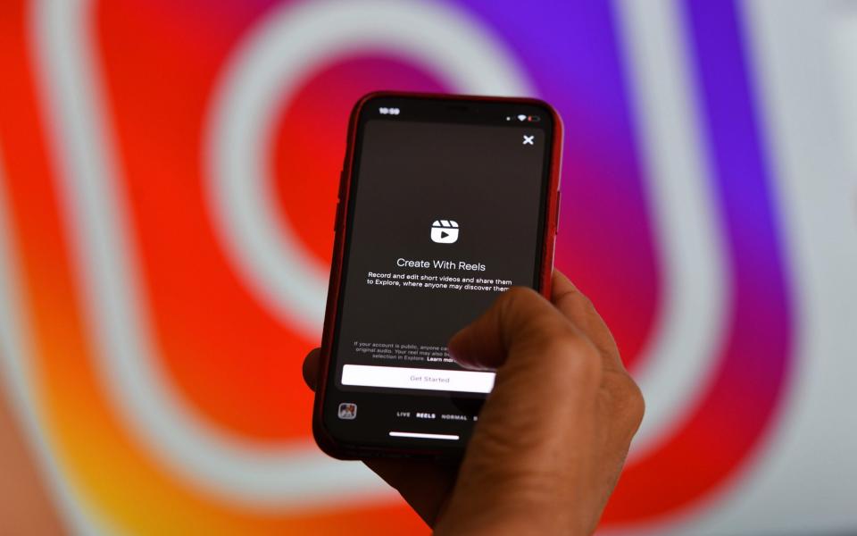 This illustration picture shows Instagram's new video feature "Reels" on a smartphone in front of a screen showing an Instagram logo, on August 6, 2020 in Los Angeles - Chris Delmas/AFP