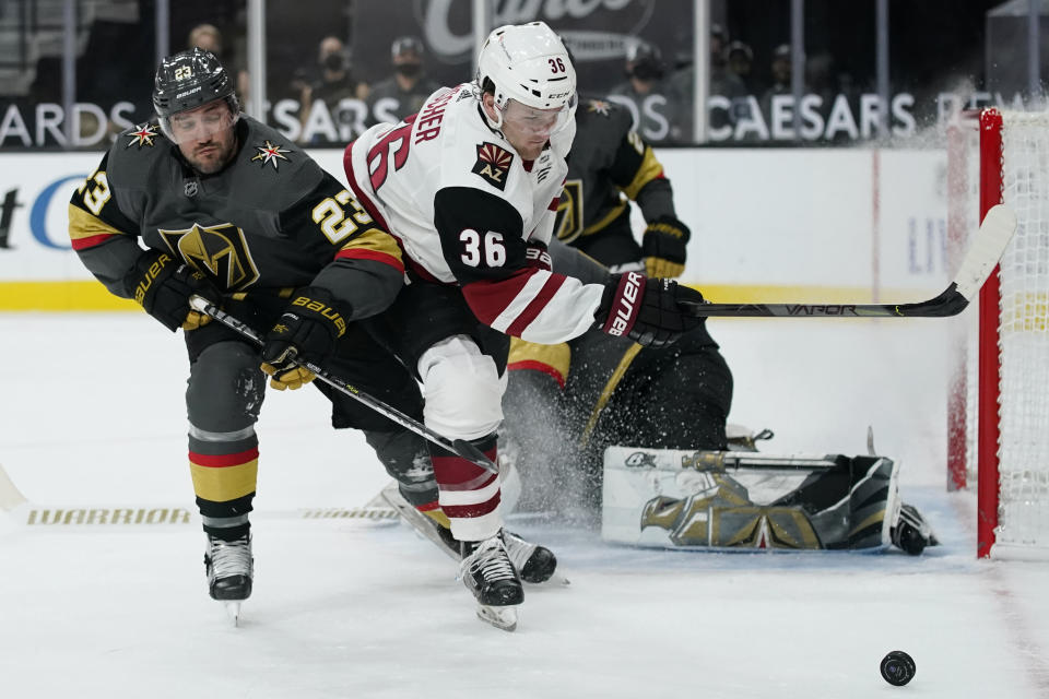 Vegas Golden Knights defenseman Alec Martinez (23) vies for the puck with Arizona Coyotes right wing Christian Fischer (36) during the third period of an NHL hockey game Monday, Jan. 18, 2021, in Las Vegas. (AP Photo/John Locher)