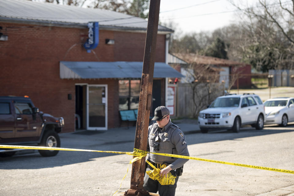 A law enforcement officer removes crime scene tape in front of Mac's Lounge, the scene of an early morning bar shooting, Sunday, Jan. 26, 2020, in Hartsville, S.C. (AP Photo/Sean Rayford)