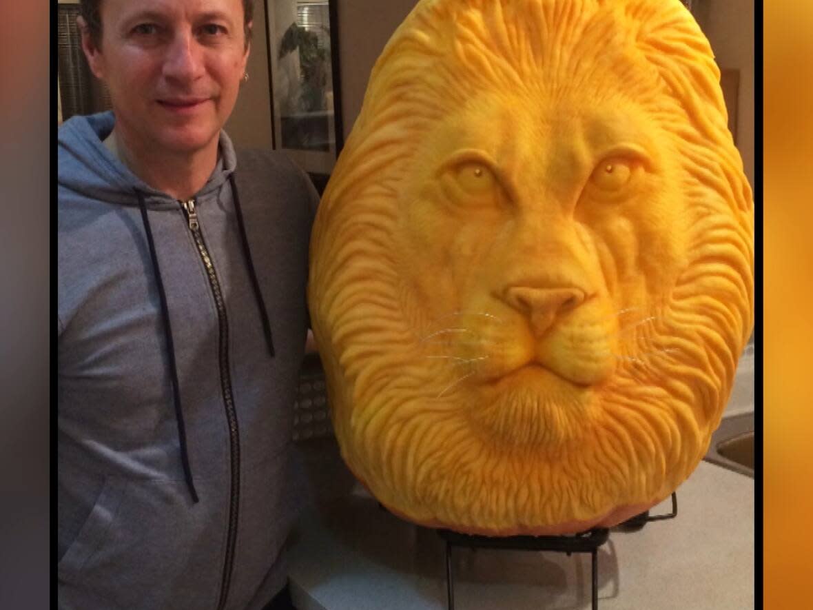 Clive Cooper and one of his many intricate pumpkin carvings, a lion.  (Submitted by Sharon Smith Cooper - image credit)