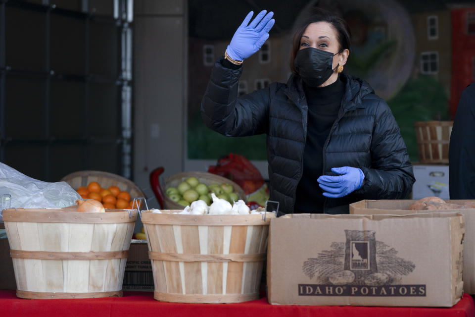 La vicepresidenta electa Kamala Harris saluda mientras llena unas bolsas con alimentos para aquellos en necesidad, el lunes 18 de enero de 2021, en Washington. (AP Foto/Jacquelyn Martin)