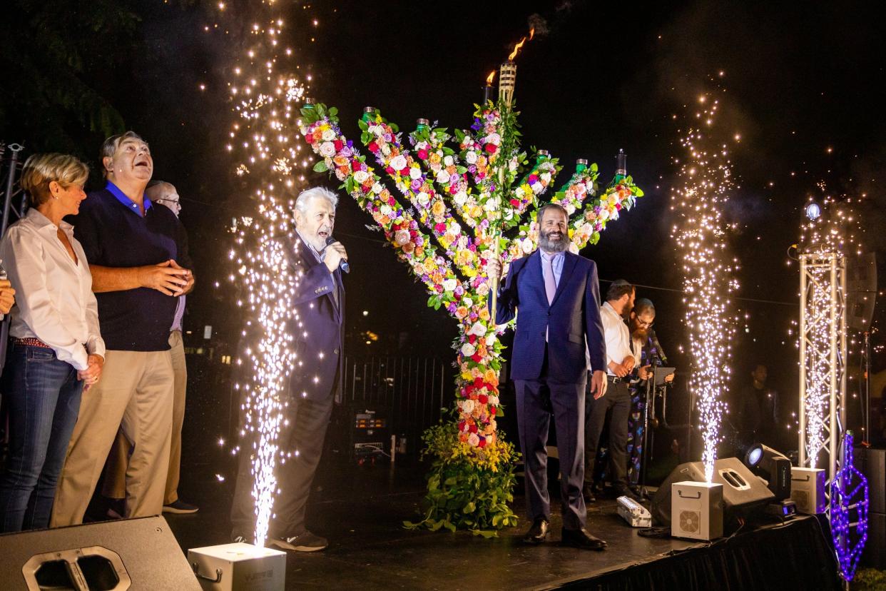 Rabbi Moshe E. Scheiner, right, lights the menorah during the Hanukkah in Bradley Park event in 2020.