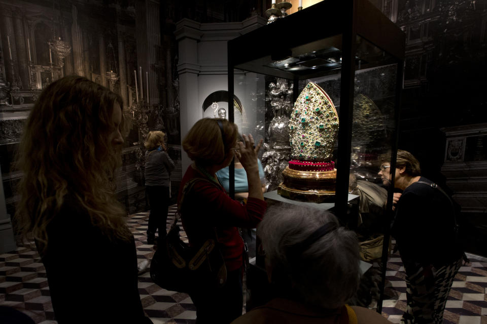 Visitors look at a Mitre put on display as part of the exhibition "Naples' Treasure. Masterpieces from the Museum of Saint Januarius", at the Fondazione Roma Museum, in Rome's Palazzo Sciarra, Wednesday, Oct. 30, 2013. The Mitre was created in 1713 by goldsmith Matteo Treglia and it contains 3328 diamonds and 198 emeralds amongst other precious stones. (AP Photo/Andrew Medichini)