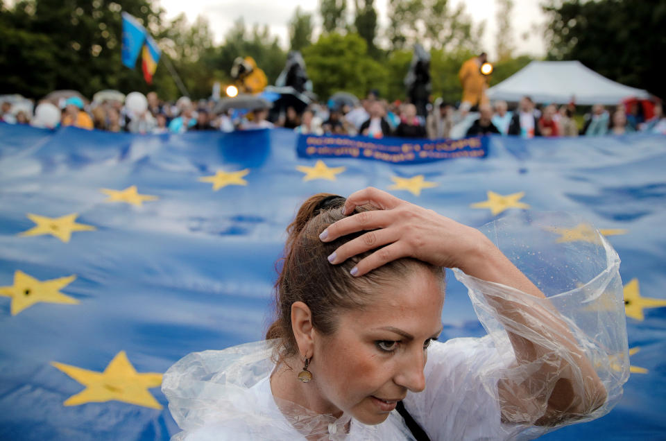 A woman runs her hand through her hair, backdropped by a European Union flag, during a 2020 USR PLUS alliance European Parliament elections rally, in Bucharest, Romania, Friday, May 24, 2019. Romanians will vote on Sunday, May 26, in the European Parliament elections. (AP Photo/Vadim Ghirda)