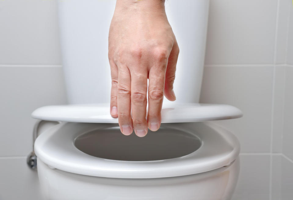 hand lifting a toilet seat