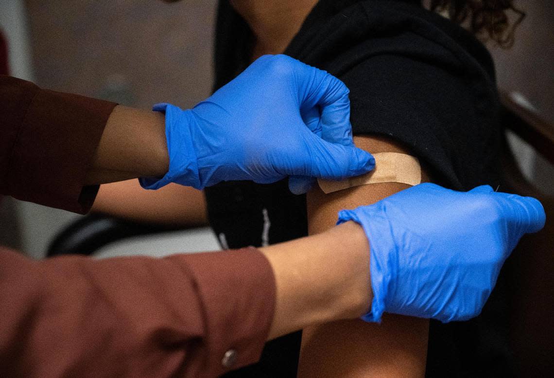 Bartell Drugs head pharmacist Nimo Ahmed places a bandage on Makenzie Porter’s, 11, arm after administering a dose of the Pfizer vaccine at the store in University Place, Wash. on Thursday, July 14, 2022.