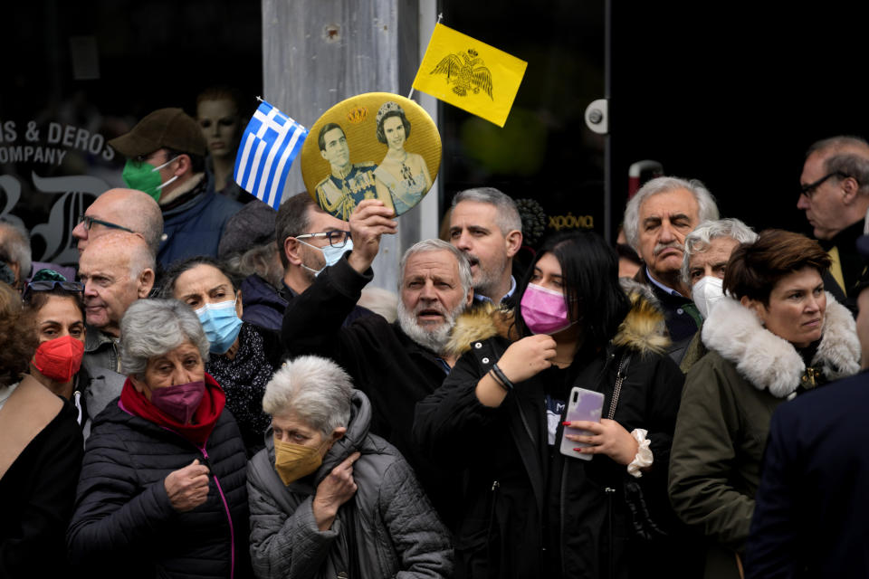 A man holds a picture of the former king of Greece Constantine with his wife Queen Anne-Marie, as wait in the Chapel of Saint Eleftherios as the coffin of the former king of Greece Constantine II lies in repose in Athens, Monday, Jan. 16, 2023. Constantine died in a hospital late Tuesday at the age of 82 as Greece's monarchy was definitively abolished in a referendum in December 1974. (AP Photo/Petros Giannakouris)