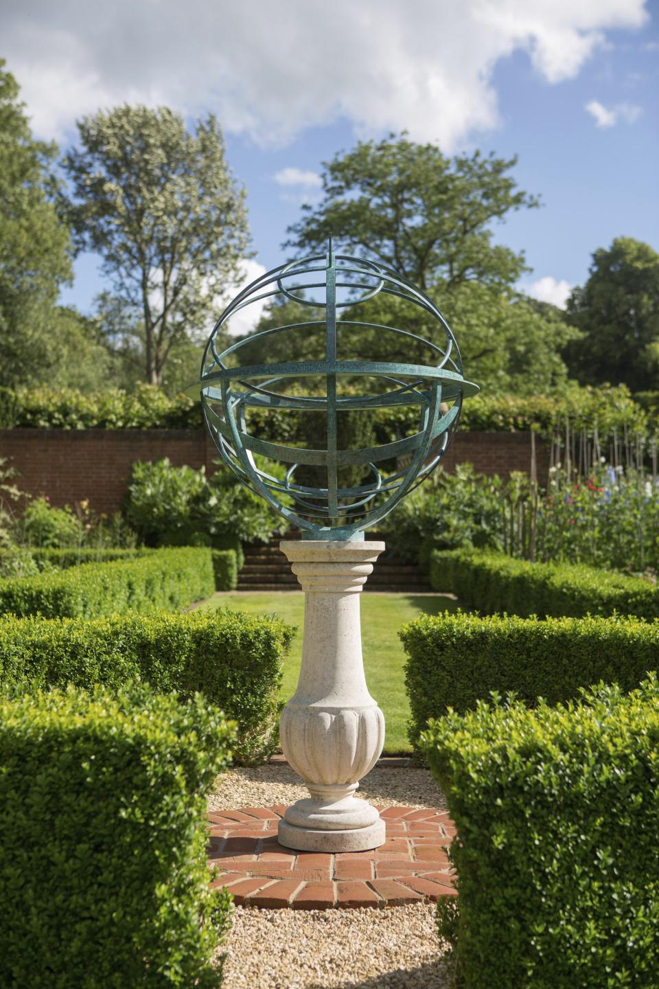 This photo shows one of British designer David Harber's armillary spheres. Harber began his storied career creating armillary spheres, like the one shown here, and he still loves creating them. Homeowners can order the bronze, steel or brass spheres etched with favorite quotes, names, home coordinates or other bespoke engravings. (Clive Nichols/David Harper via AP)