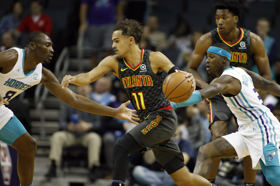 Atlanta Hawks' Trae Young (11) moves the ball past Charlotte Hornets' Terry Rozier (3) and away from Bismack Biyombo (8) during the first half of an NBA basketball game in Charlotte, N.C., Sunday, Dec. 8, 2019. (AP Photo/Bob Leverone)