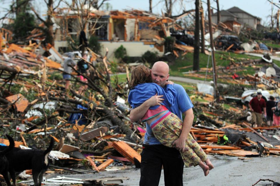 A man carries a young girl who was rescued after being trapped with her mother in their home after a tornado hit Joplin, Mo., May 22, 2011. A new study says warming will fuel more supercells or tornados in the United States and that those storms will move eastward from their current range.