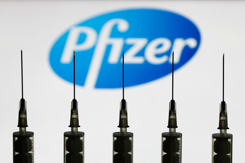 Medical syringes are seen with Pfizer company logo displayed on a screen in the background in this illustration photo taken in Poland on October 12, 2020. (Photo illustration by Jakub Porzycki/NurPhoto via Getty Images)