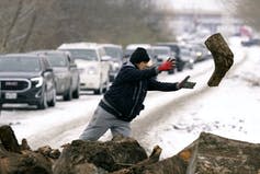 A woman throws a log of wood through the air