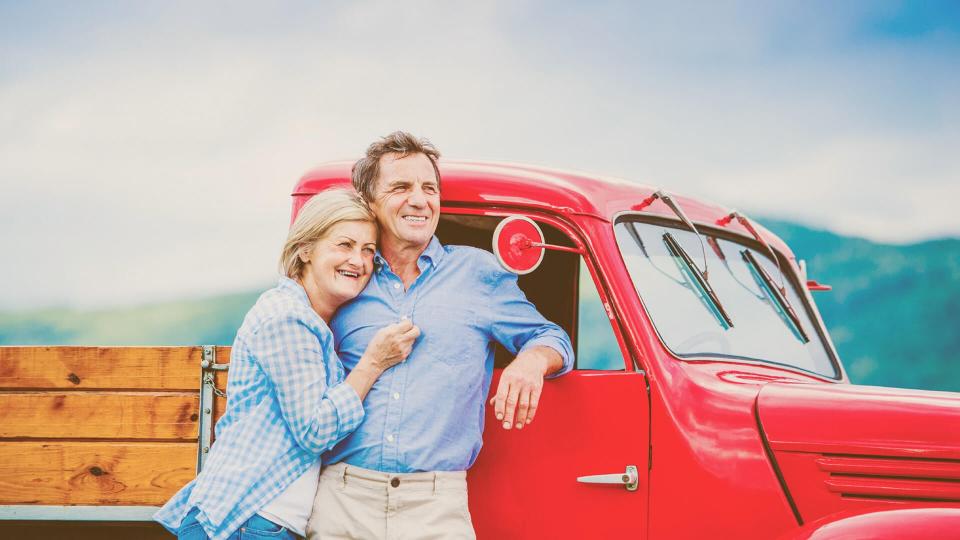 older couple standing beside a vintage red truck