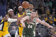 Indiana Pacers' Buddy Hield (24) and Milwaukee Bucks' Pat Connaughton (24) via for a loose ball during the first half of an NBA basketball game, Friday, Jan. 27, 2023, in Indianapolis. (AP Photo/Darron Cummings)