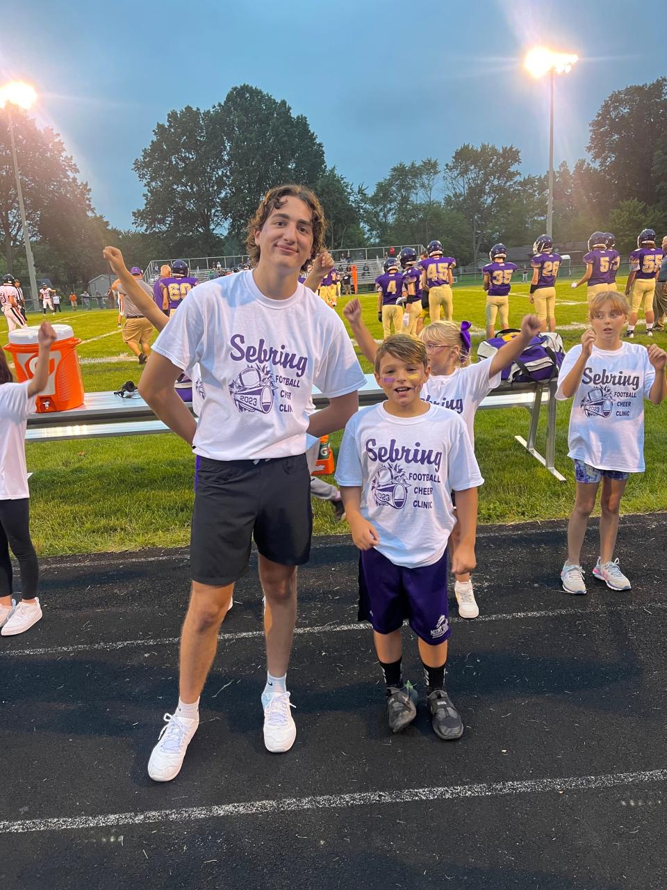 Sebring senior cheerleader Johnathon Billingsley, left, stands during a recent football game with fourth grader Zolan Sayre, who took part in a recent Sebring cheer clinic.