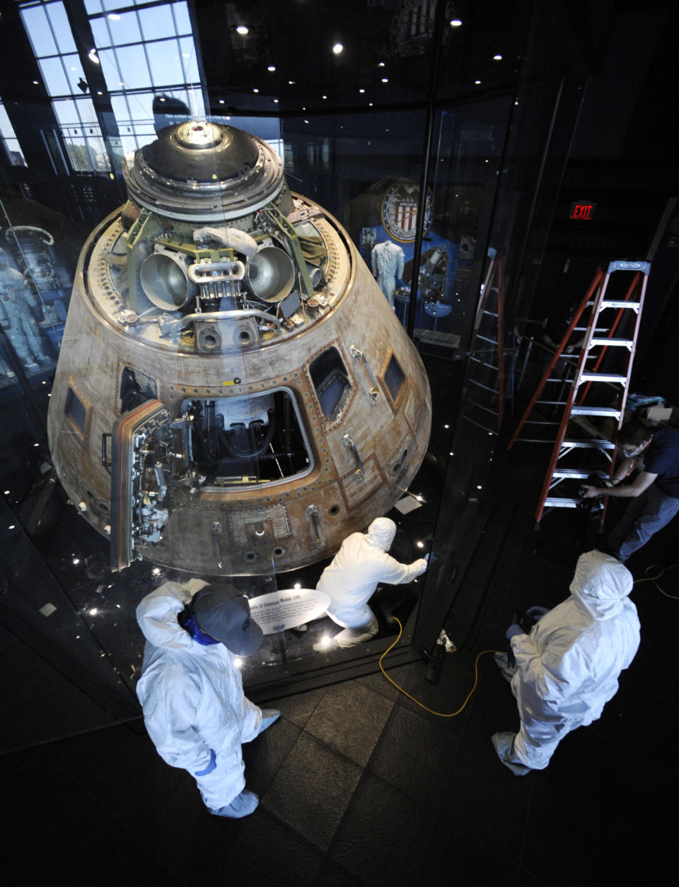 Workers surround the Apollo 16 lunar capsule while cleaning out its case at the U.S. Space and Rocket Center in Huntsville, Ala., on Tuesday, Feb. 1, 2022. Following a break in routine maintenance because of the COVID-19 pandemic, the museum is sprucing up the antique spaceship before events marking the 50th anniversary of its flight to the moon in 1972. (AP Photo/Jay Reeves)