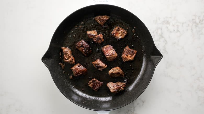 steak pieces in frying pan