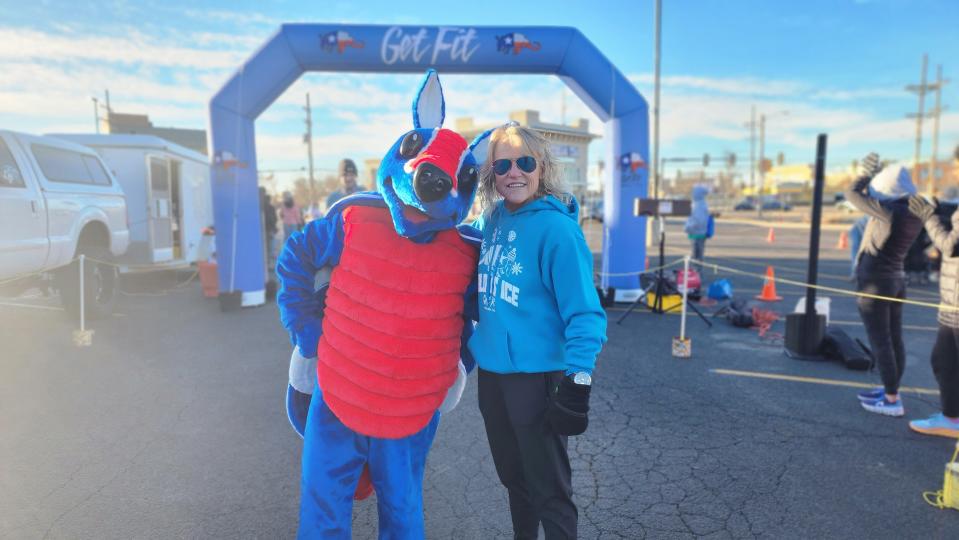 Karen Roberts, owner of specialty running store Get Fit, stands at the finish line with the store's mascot Shelden the Armadillo on Saturday at the Cold As Ice run in Amarillo.