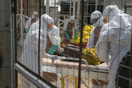 British health workers lift a newly admitted Ebola patient onto a wheeled stretcher in to the Kerry town Ebola treatment centre outside Freetown December 22, 2014. REUTERS/Baz Ratner