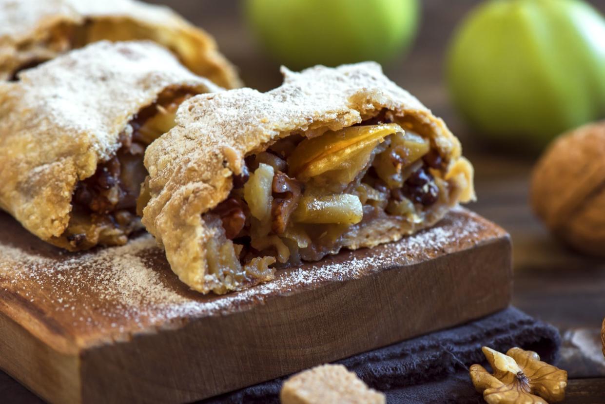 Homemade apple strudel with apples, raisin and walnuts, vegetarian delicious pastry over rustic wooden board