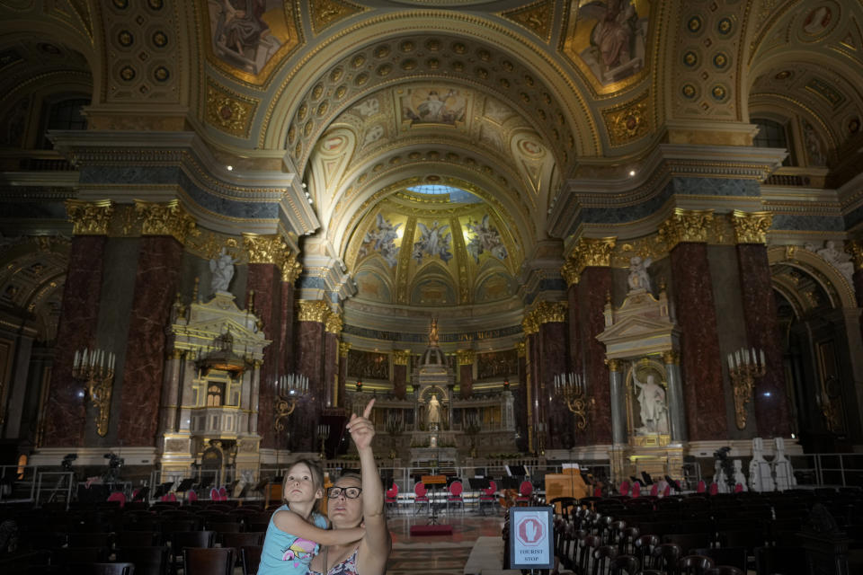 A woman holds a little girl inside the St. Stephen's Basilica in Budapest, Hungary, Friday, Sept. 10, 2021. Pope Francis is making his first foreign trip since undergoing intestinal surgery in July. His four-day visit to Hungary and Slovakia starting Sunday will not only test his health but also provide what may be one of the most awkward moments of his papacy — a meeting with Hungarian Prime Minister Viktor Orban, the sort of populist, right-wing leader Francis scorns. (AP Photo/Vadim Ghirda)