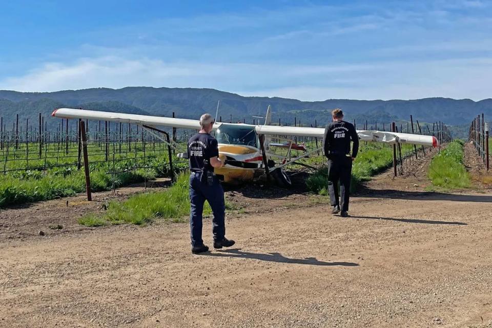 Two Santa Barbara County firefighters respond to the scene Saturday, March 18, 2023, after a small plane made an emergency landing in a vineyard adjacent to the Santa Ynez Airport.