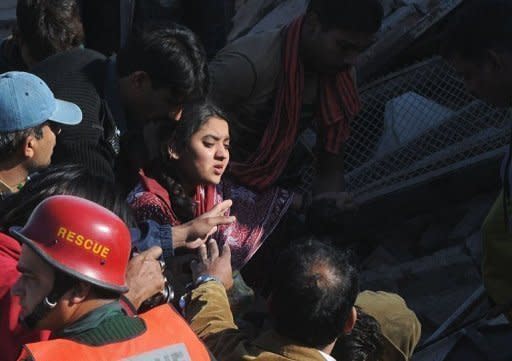 Pakistani rescue workers remove an injured woman from a collapsed factory in Lahore on Monday. Rescuers on Tuesday pulled more survivors and bodies from the rubble of a factory that collapsed in the city of Lahore, as the death toll rose to 19 after the disaster