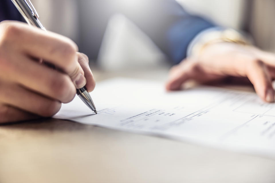 Person reviewing a document and writing with a pen