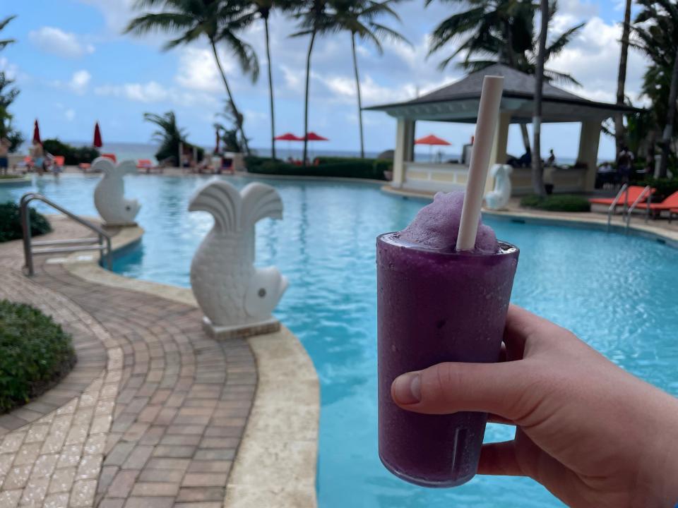 writer holding purple drink in front of pool