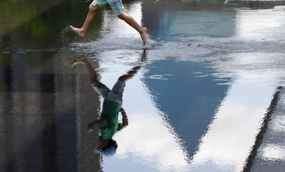 David Zabala, 5, runs across a reflecting pool in Sammons Park outside the Windspear Opera House in the arts district of downtown Dallas, Thursday, July 12, 2012. Dallas is a city that likes to do things big, but that doesn’t mean you’ll have to sell the ranch to have a good time here. (AP Photo/LM Otero)