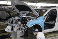 In this April 8, 2020, photo, employees work on a car assembly line at the Dongfeng Honda Automobile Co., Ltd factory in Wuhan in central China's Hubei province. The United States, Japan and France are prodding their companies to rely less on China to make the world’s smartphones, drugs and other products. But even after the coronavirus derailed global trade, few are willing to give up access to its skilled workers, vast market and efficient suppliers by moving factories closer to home.(AP Photo/Ng Han Guan)