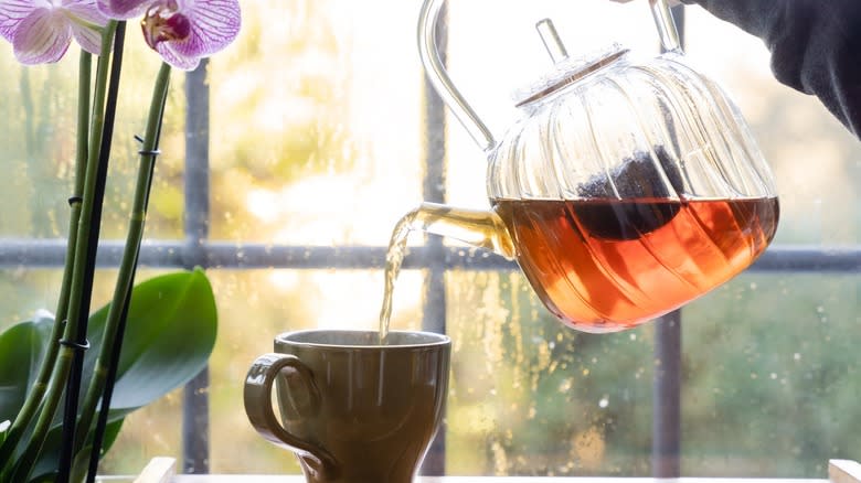 Tea being poured from a glass pitcher into a mug