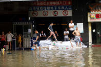 People stand on a pile of sand bags at an entrance of a garage at a flooded area after Typhoon Hato hits Dongguan, Guangdong province, China August 23, 2017. REUTERS/Stringer